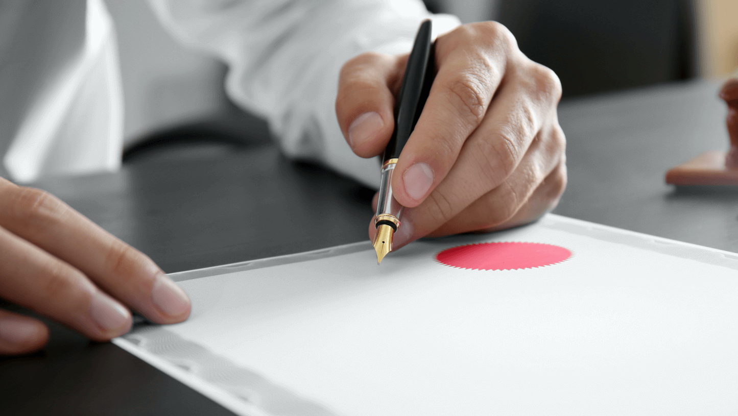 Photo of pen hovering over a blank diploma