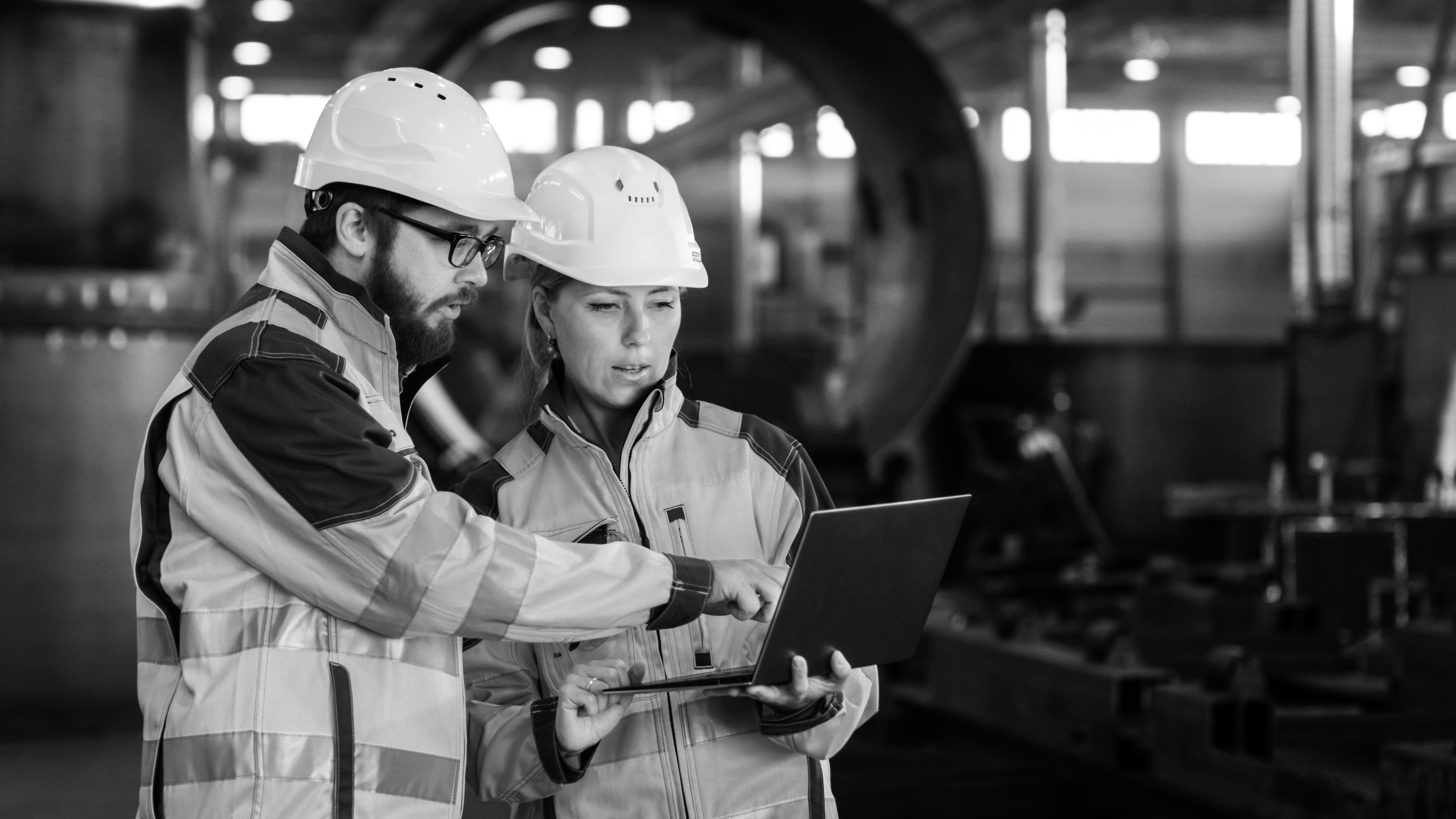Two people in safety gear looking at laptop
